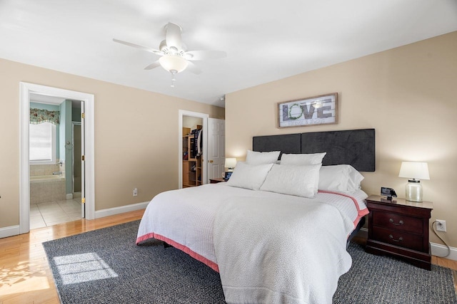 bedroom with a spacious closet, ceiling fan, baseboards, and wood finished floors