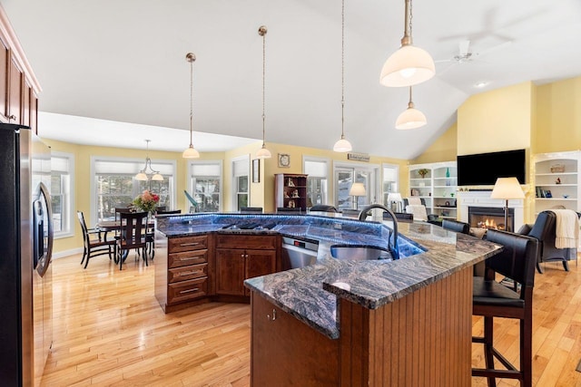 kitchen featuring a sink, open floor plan, a lit fireplace, and stainless steel appliances