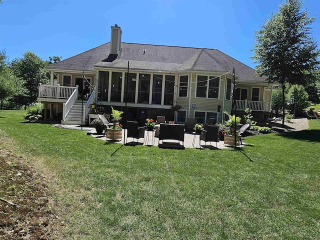 rear view of property with stairs, a chimney, a yard, a sunroom, and a patio