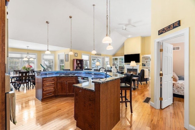 kitchen with a kitchen bar, light wood-style flooring, visible vents, and a sink