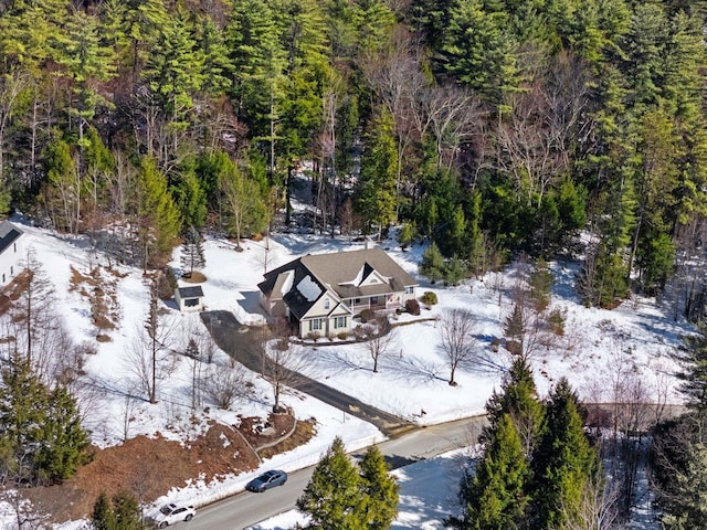 snowy aerial view featuring a wooded view