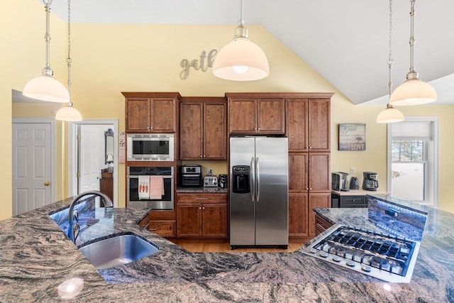 kitchen featuring a sink, decorative light fixtures, appliances with stainless steel finishes, and dark stone countertops