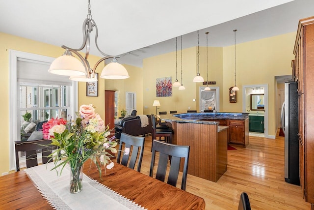 dining area featuring a high ceiling, baseboards, and light wood-type flooring