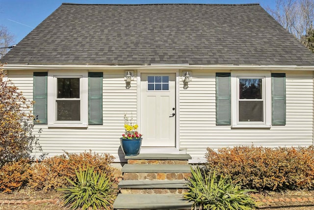 doorway to property featuring roof with shingles