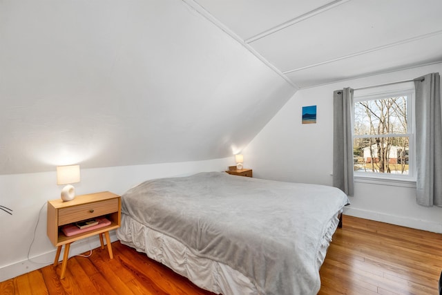 bedroom with vaulted ceiling, baseboards, and wood-type flooring