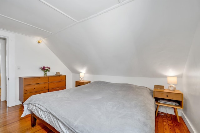 bedroom featuring baseboards, lofted ceiling, and light wood finished floors