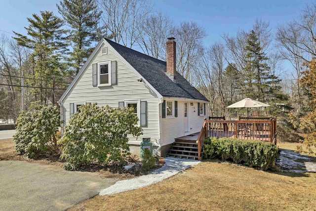 back of house with a wooden deck, a lawn, roof with shingles, and a chimney