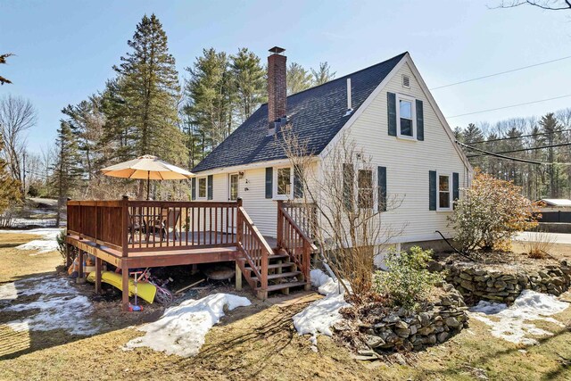 rear view of house featuring a wooden deck, roof with shingles, and a chimney