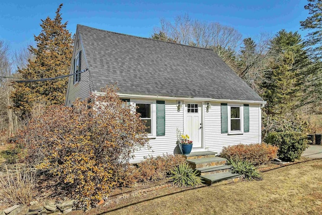 new england style home featuring a front lawn and a shingled roof