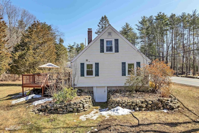 view of side of home featuring a wooden deck and a chimney