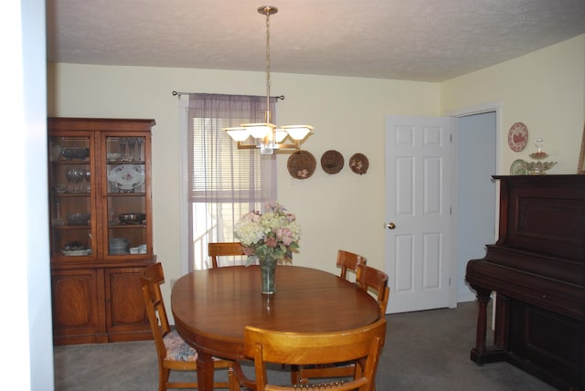 carpeted dining area with a notable chandelier and a textured ceiling