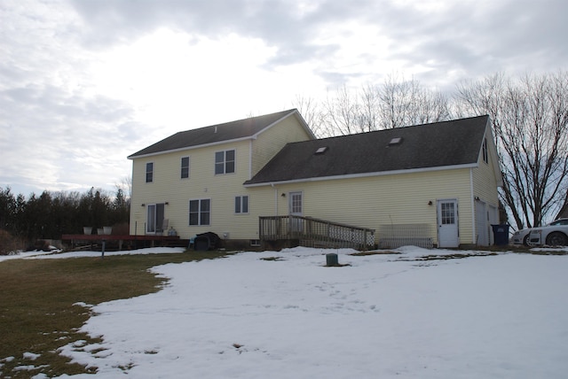 snow covered house featuring a wooden deck and a garage