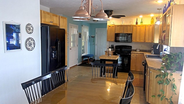 kitchen featuring backsplash, decorative light fixtures, light countertops, black appliances, and a sink