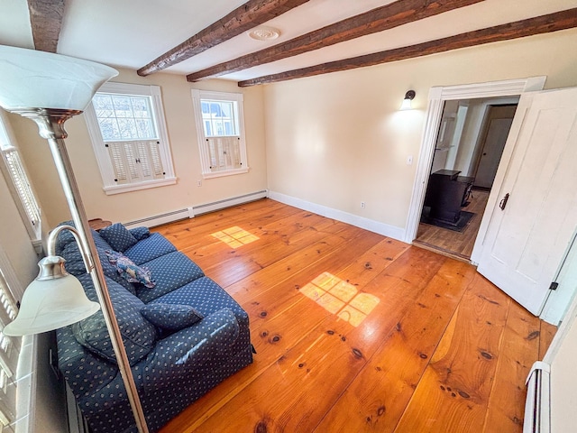 living room with a baseboard heating unit, beam ceiling, light wood-style flooring, and baseboards