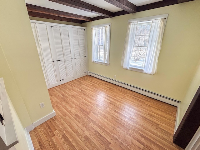 unfurnished bedroom featuring beam ceiling, a closet, light wood-style floors, baseboards, and baseboard heating