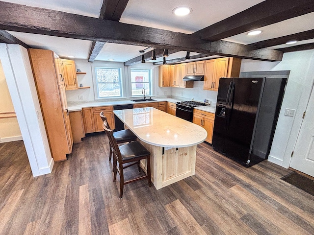 kitchen featuring a sink, black appliances, light countertops, dark wood-type flooring, and under cabinet range hood