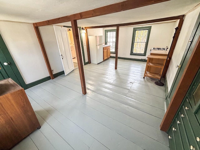 basement with light wood finished floors, baseboards, and freestanding refrigerator