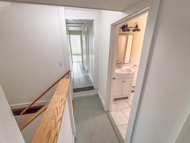 hallway featuring baseboards and a sink