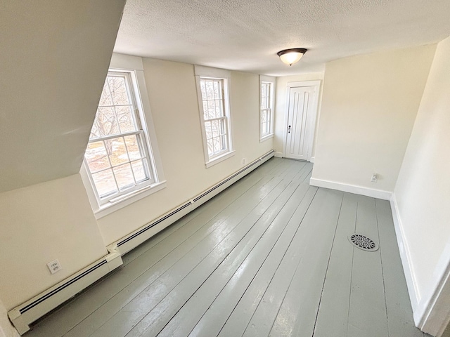 spare room featuring a textured ceiling, baseboards, and wood-type flooring