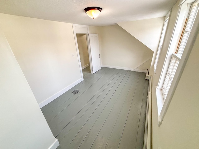 bonus room with dark wood-style floors, a healthy amount of sunlight, and baseboards