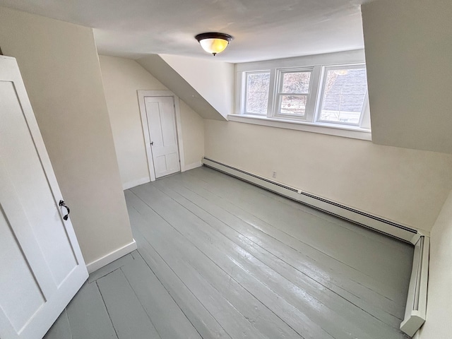 additional living space featuring a baseboard heating unit, lofted ceiling, baseboards, and wood finished floors