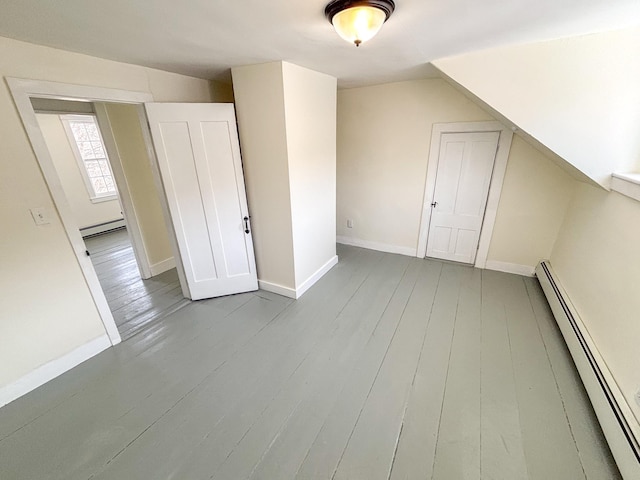 additional living space with wood finished floors, baseboards, vaulted ceiling, a baseboard heating unit, and baseboard heating