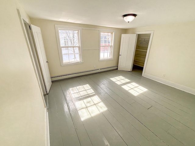 unfurnished bedroom featuring hardwood / wood-style floors, baseboards, and baseboard heating