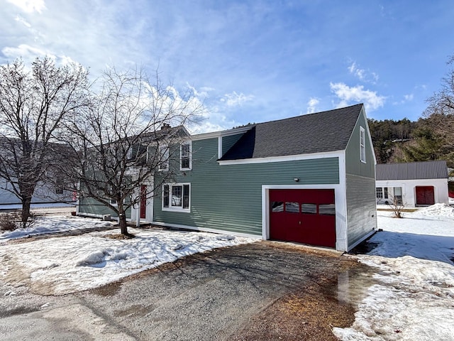 view of front of property featuring a garage, driveway, and a shingled roof