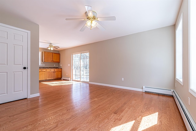 unfurnished living room featuring light wood finished floors, a baseboard heating unit, and baseboards