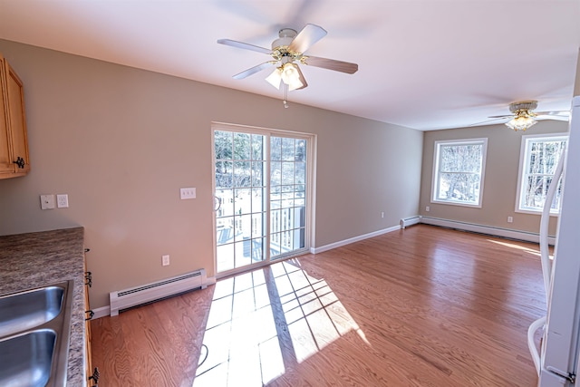 kitchen featuring a sink, a baseboard radiator, a wealth of natural light, and light wood finished floors