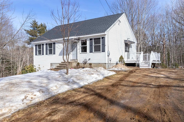 ranch-style home with a wooden deck and roof with shingles