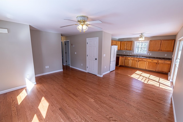 kitchen with ceiling fan, baseboards, freestanding refrigerator, and light wood-style floors