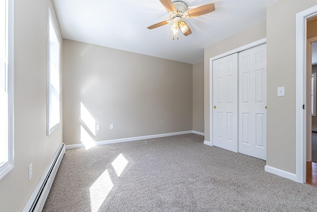 unfurnished bedroom featuring a baseboard radiator, baseboards, a closet, and carpet flooring