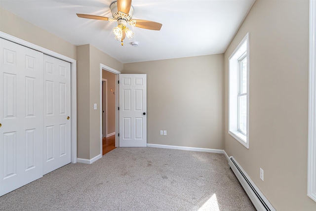 unfurnished bedroom featuring a closet, baseboard heating, carpet flooring, and baseboards