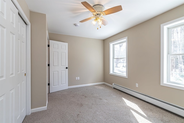 unfurnished bedroom featuring a ceiling fan, baseboards, a closet, light colored carpet, and baseboard heating