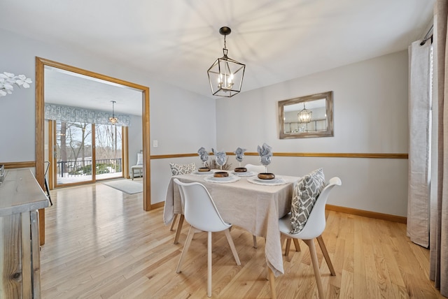 dining space with light wood-type flooring, baseboards, and a notable chandelier