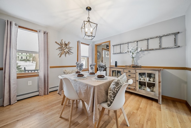 dining area featuring light wood finished floors, baseboards, a baseboard heating unit, and an inviting chandelier