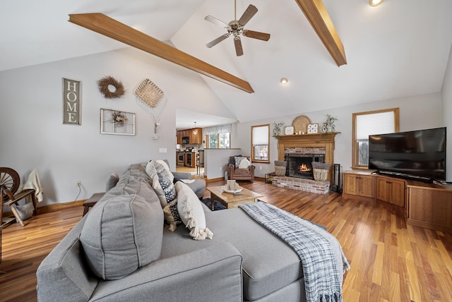 living room featuring a fireplace, beam ceiling, light wood-style floors, and high vaulted ceiling