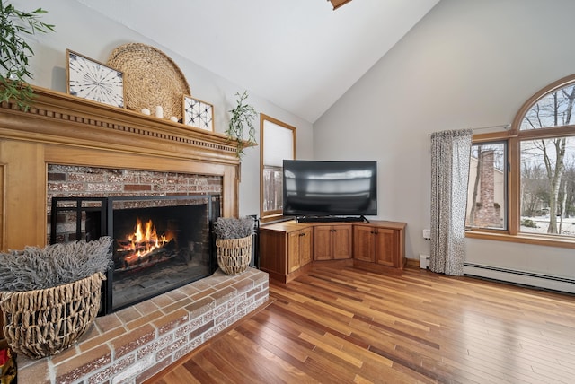 living area featuring high vaulted ceiling, a fireplace, and light wood finished floors