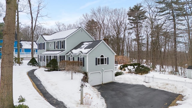 view of front of home with aphalt driveway, an attached garage, and a chimney