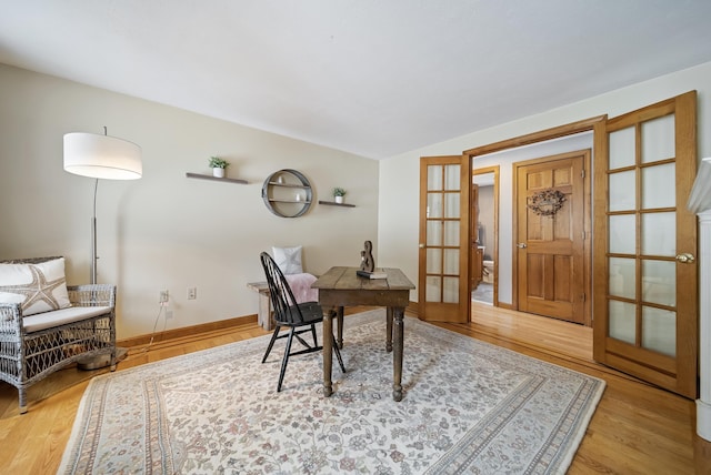 home office with wood finished floors, french doors, and baseboards