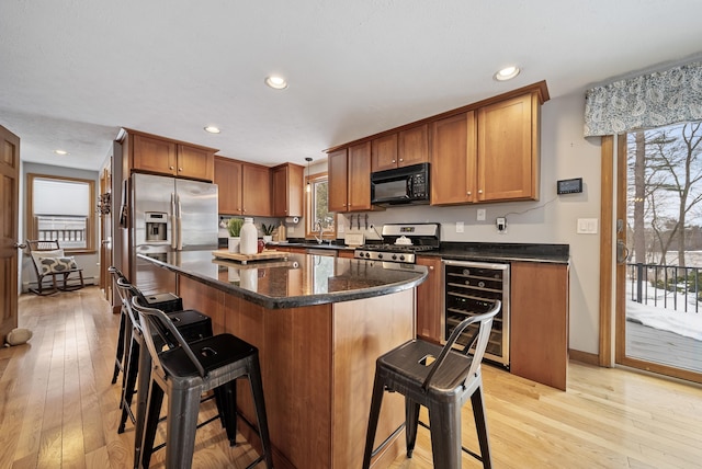 kitchen with a breakfast bar, light wood-style flooring, a kitchen island, stainless steel appliances, and wine cooler