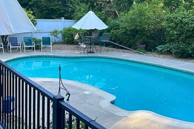 pool with a patio area and fence