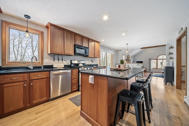 kitchen with a center island, a breakfast bar area, appliances with stainless steel finishes, brown cabinetry, and a sink