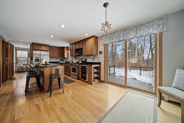 kitchen with light wood-style floors, stainless steel appliances, dark countertops, and a breakfast bar area