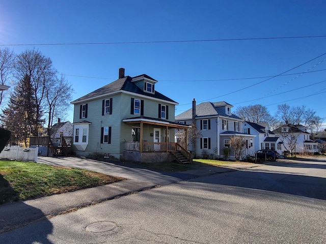 traditional style home with a residential view, covered porch, a chimney, and a front lawn