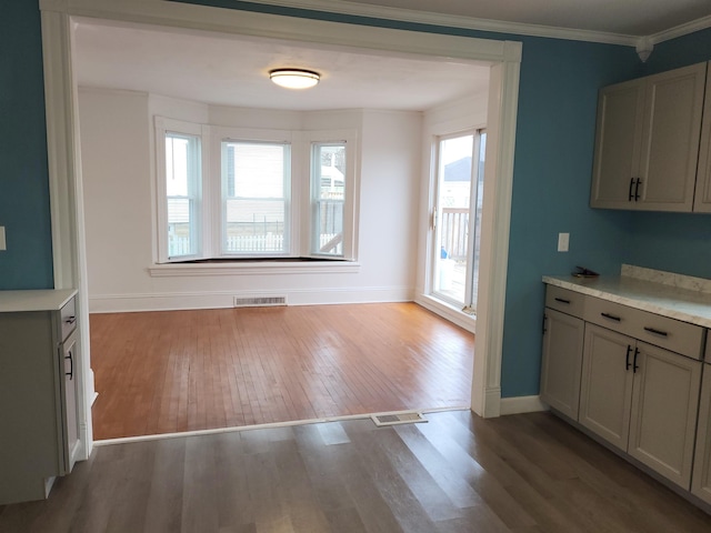 kitchen featuring visible vents, light countertops, crown molding, and wood finished floors