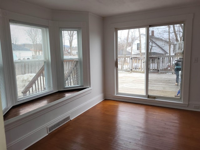 unfurnished dining area featuring visible vents, baseboards, and hardwood / wood-style floors