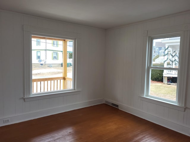 spare room featuring a wealth of natural light, visible vents, and hardwood / wood-style flooring