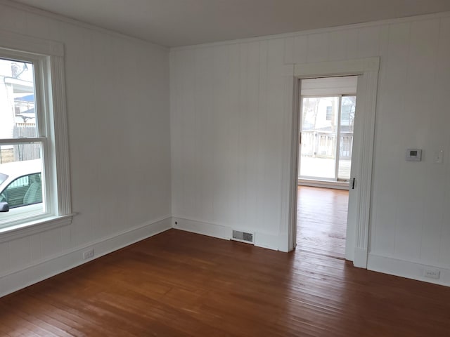 spare room featuring visible vents, crown molding, baseboards, and wood finished floors